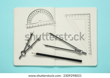 Different rulers, pencils, compasses and notebook on turquoise background, flat lay