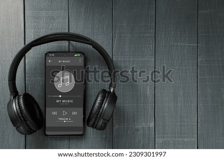 Music player in phone, wireless headphones and phone. Black headphones and a music player on the phone screen. Copy space