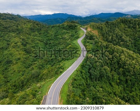 Taken from a drone camera angle at Sky Road, Road No. 3, Unseen, Nan Province, Thailand, meandering along the ridge of the forest. The view is very beautiful. The rainy season is green. Royalty-Free Stock Photo #2309310879