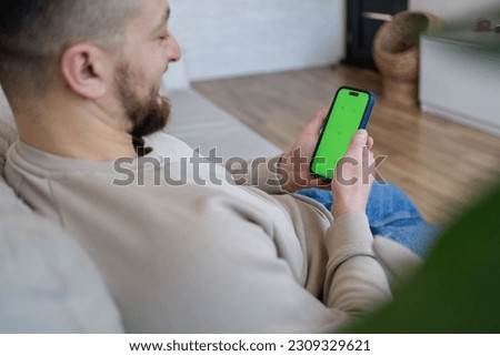 Man using smartphone with chroma key screen at home.