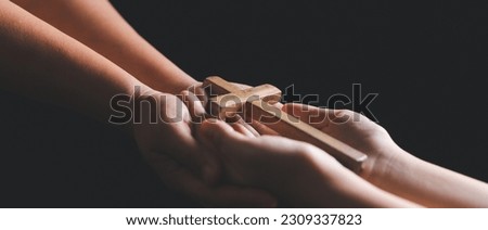 Woman's hand with cross. Concept of hope, faith, christianity, religion, church online. Person holding christian cross to making pray indoors. Believe and faith for christian people.