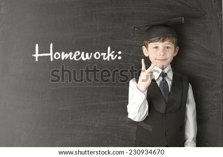 Cheerful little boy on blackboard. Looking at camera. School concept
