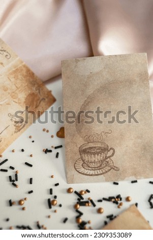 Textured paper cards with coffee drops and a picture of a coffee cup on a pink silk fabric background. Background image with paper coffee cards