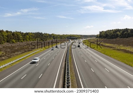 Dutch six lane highway with a few cars seen from above with infrastructure through natural reserve area. Commute transit asphalt corridor interstate. Royalty-Free Stock Photo #2309371403