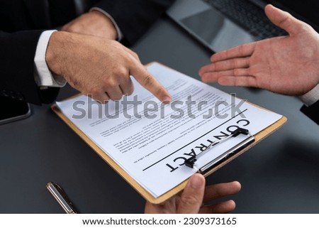 Closeup business deal meeting, businessman carefully reviewing terms and condition of contract agreement papers in office. Corporate lawyer give consultation on contract deal. Fervent