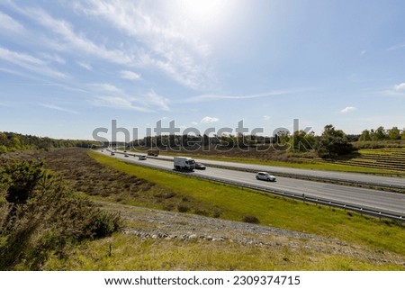 Sunny day Dutch six lane highway with a few cars seen from above with infrastructure through natural reserve area. Commute transit asphalt corridor interstate. Royalty-Free Stock Photo #2309374715
