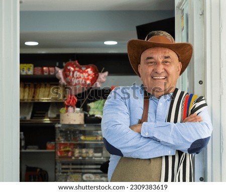 Colombian cafeteria owner leaning on the front door Royalty-Free Stock Photo #2309383619