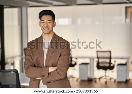 Young happy Asian business man looking at camera standing in office. Smiling confident professional Japanese businessman executive, successful software engineer or entrepreneur wearing suit, portrait. Royalty-Free Stock Photo #2309391965