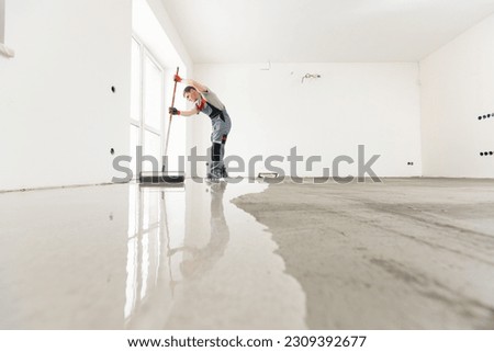 Leveling with mixture of cement for floors. Worker use screed concrete epoxy for level. Royalty-Free Stock Photo #2309392677