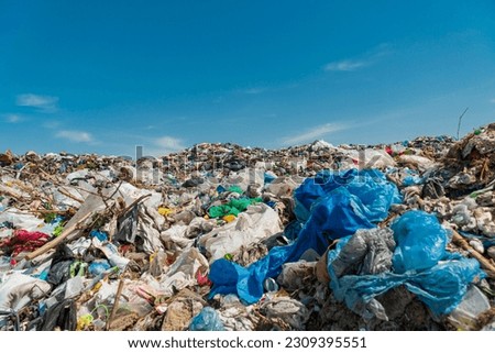 A pile of garbage in a landfill against a blue sky. Royalty-Free Stock Photo #2309395551