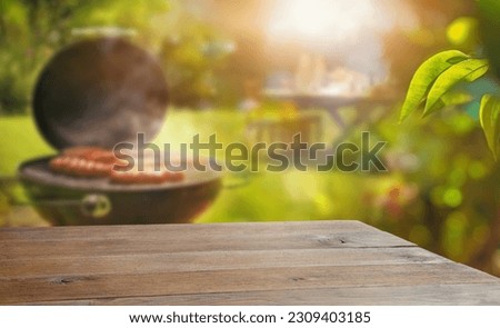 summer time in backyard garden with grill BBQ, wooden table, blurred background Royalty-Free Stock Photo #2309403185
