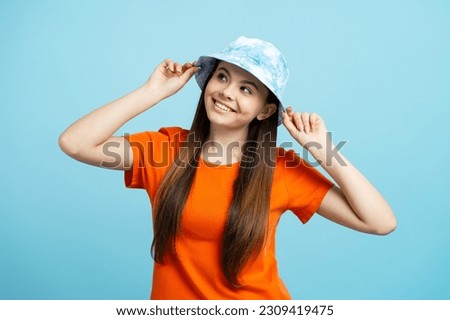 Smiling caucasian teenage girl wearing stylish panama hat, looking away, planning vacation, isolated on blue background. Summer travel concept