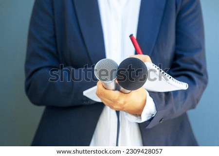 Journalist at media event or news conference, holding microphone, writing notes. Broadcast journalism concept. Royalty-Free Stock Photo #2309428057