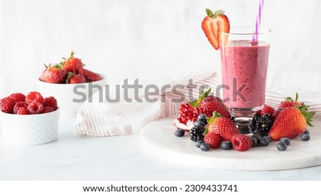 A very berry smoothie surrounded by berries and garnished with a strawberry. Royalty-Free Stock Photo #2309433741