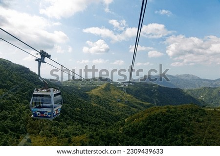 A panoramic view from a gondola of Ngong Ping 360 cable car, overlooking green lush forests on the mountainside and the giant Tian Tan Buddha Statue on a mountaintop in Lantau Island, Hong Kong, China Royalty-Free Stock Photo #2309439633