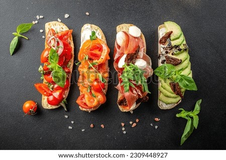 a set of bruschetta with prosciutto, salmon, tomatoes and avocado on a wooden board, banner, menu, recipe place for text, top view,