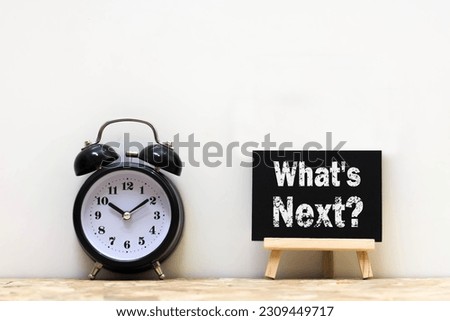 Post note word What's next on alarm clock wood desk white background. 
ฺBlackboard message What's next and watch on wooden table for copy space.
Business concept.