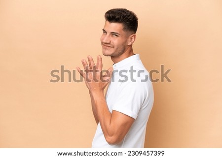 Young caucasian man isolated on beige background scheming something Royalty-Free Stock Photo #2309457399