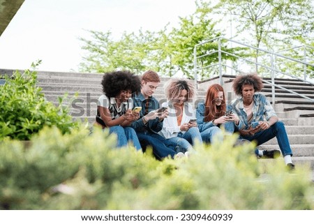 Group of students sitting around the university campus looking only at their cell phones. Concept: digital age, unsociable, smartphone