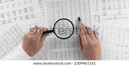 Woman holding a magnifying glass pointing at numbers on financial documents. ?oncept of finance, search and accounting. Royalty-Free Stock Photo #2309461161