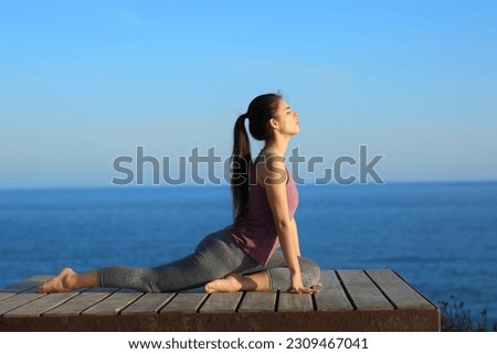 Profile of a woman doing yoga exercises on the beach Royalty-Free Stock Photo #2309467041