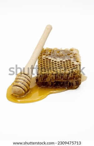 Honeycomb with honey and honey dipper isolated on white background