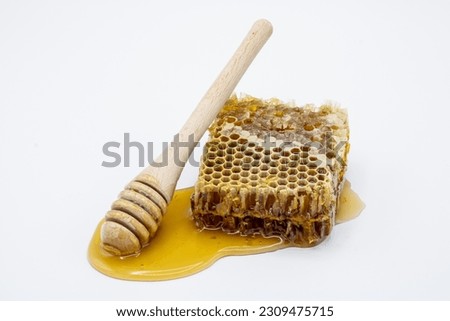 Honeycomb with honey and honey dipper isolated on white background