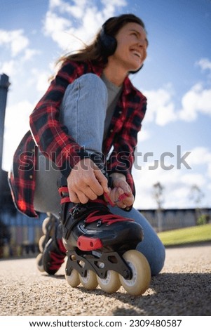 Close-up wide angle view of a woman tying her inline skate laces with the skates as main subject
