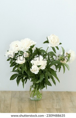 Large bouquet of white peonies in a vase on the floor