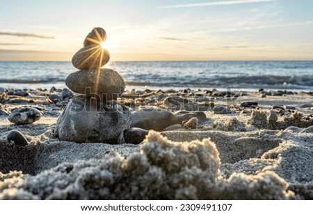 Stone pyramids and glass sphere on the dreamy Baltic Sea sand beach on Rügen to the spectacular orange sunset