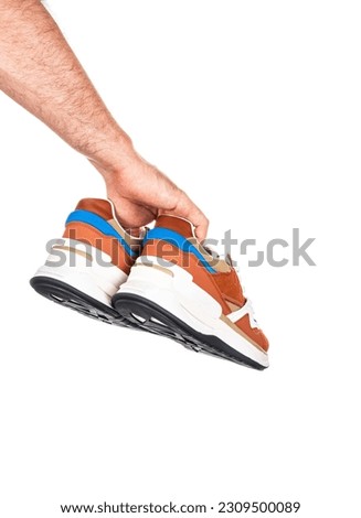 Pair of new unbranded brown shoes or sneakers in male hand isolated on white background with clipping path. High quality photo