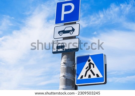 Parking sign for passenger cars indicating roadside parking with a crosswalk crossing on a concrete pole against a blue sky background