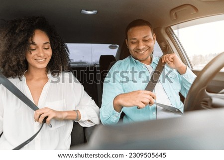 Road Safety Concept. Middle eastern couple practicing safe driving habits, wearing seat belts sitting in new car inside, enjoying comfort of vehicle. Safe Transportation And Auto Insurance Offer Royalty-Free Stock Photo #2309505645