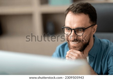 Closeup Shot Of Smiling Handsome Man In Eyeglasses Working With Laptop In Office, Millennial Male Entrepreneur Using Computer For Work, Looking At Monitor Screen, Touching Chin And Smiling Royalty-Free Stock Photo #2309505943