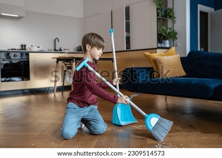 Little boy sweeping floor in living room, kid doing daily regular household chores and helping parents around house, gain important life skills. Children and housework concept Royalty-Free Stock Photo #2309514573