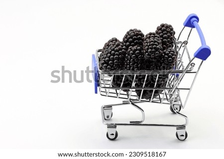 A toy shopping cart with blackberries. Healthy food concept