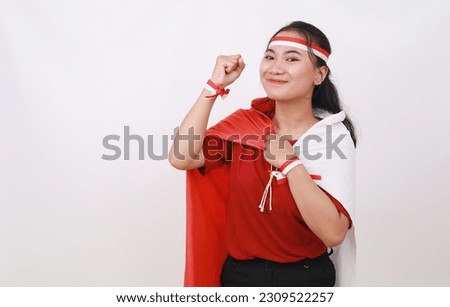 Cheerful young indonesian girl celebrate independence day while holding red white flag and fist hand Royalty-Free Stock Photo #2309522257