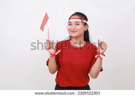 Excited young indonesian girl holding red white flag while clenched hand. Isolated on white Royalty-Free Stock Photo #2309522301