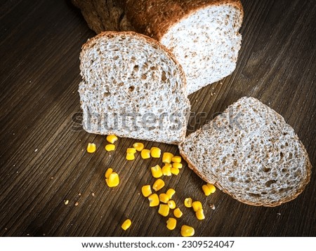 Delicious sliced corn wholemeal bread on dark ructic wood background closeup. seen at an 85-degree angle