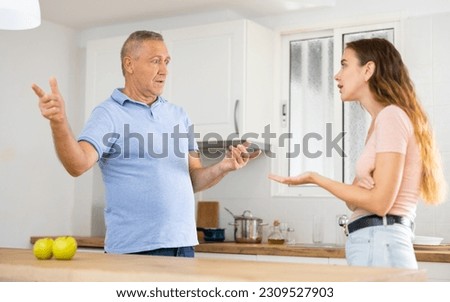 Emotional adult daughter arguing with her mature father in the kitchen Royalty-Free Stock Photo #2309527903