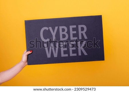 Female hand holding a cyber week poster. Studio shot.