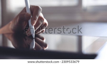 Business woman using stylus pen signing electronic document on digital tablet on office table, close up, paperless office, E-signing concept