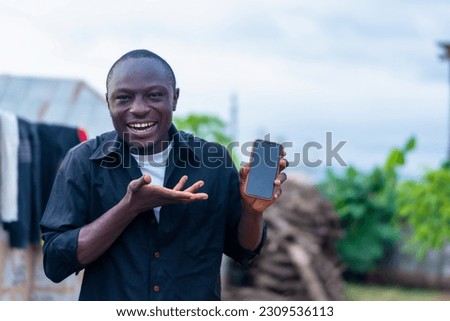 excited black african man showing smartphone with blank screen to the camera, gesturing sign of success and approval, making use of wireless technology