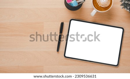 Wooden desk workplace with blank screen tablet, pen and cup of coffee, Top view flat lay with copy space.