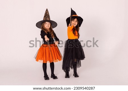 Two little girls in witch costumes having fun on Halloween on white background with copy space. Kids trick or treating