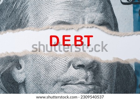 Benjamin Franklin face from USD dollar banknote behind of torn paper with debt wording for America's public debt is high and the debt ceiling needs to be raised concept.