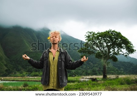 A young beautiful girl meditates, in nature, against the backdrop of mountains.
