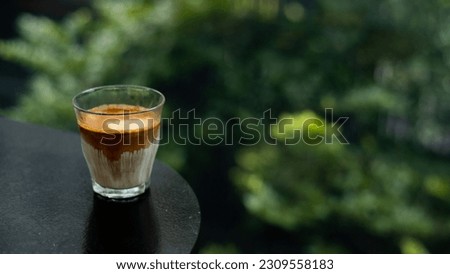 Espresso coffee in a glass on a wooden table with green background