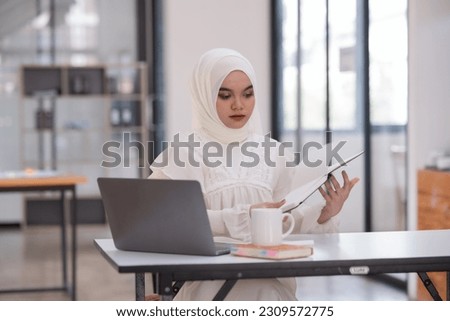 Young islamic Asian businesswoman holding notebook about business, spending money