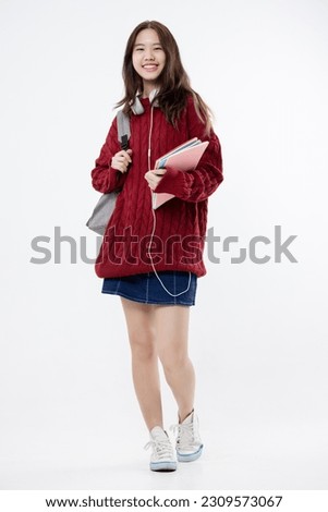 Happy beautiful Asian teen girl in red sweater with headphones isolated on white background.